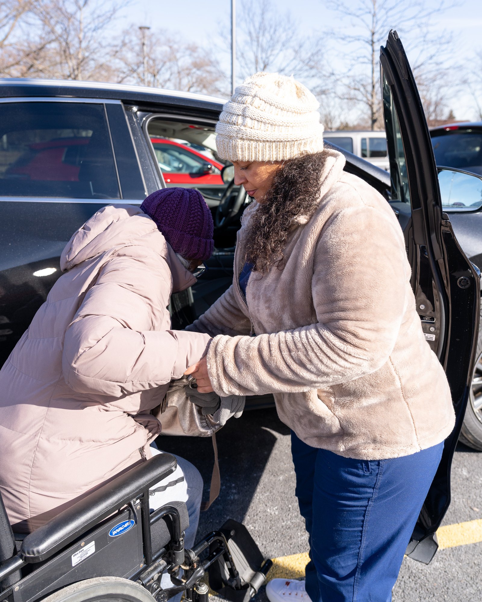 Care Partners helping a client transfer from a car into a wheelchair
