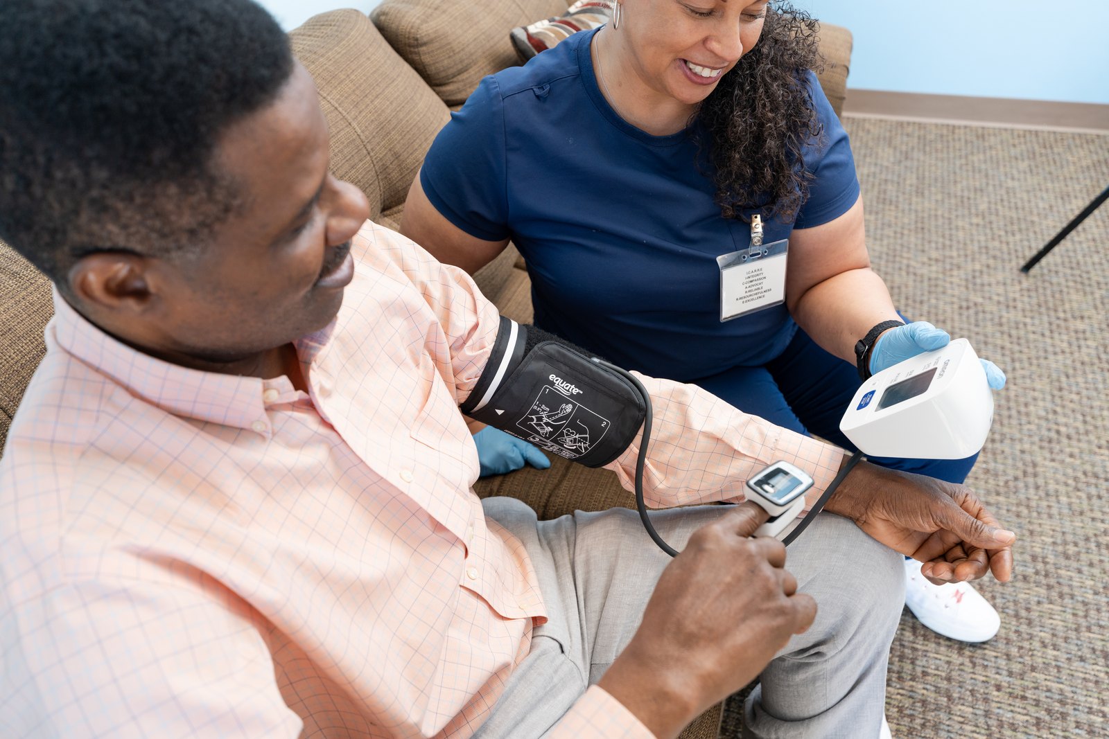 A Care Partner checking blood pressure and pulse oximetry for a client at home