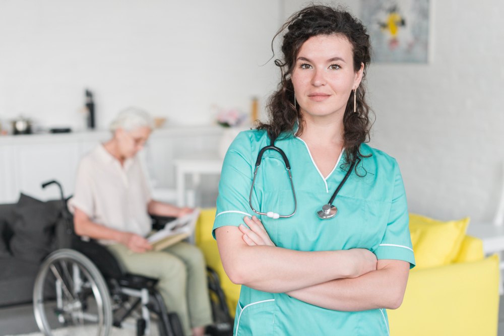 A nurse standing in a living room while a client reads nearby