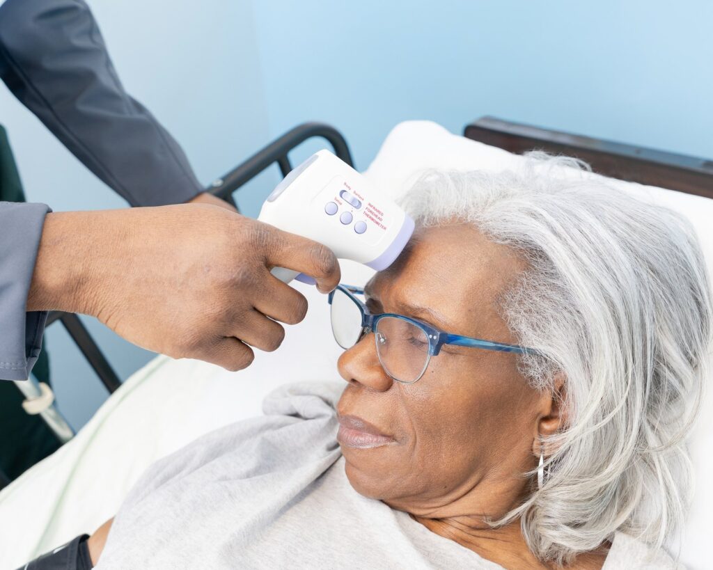 A Care Partner checking a client’s temperature during a home visit