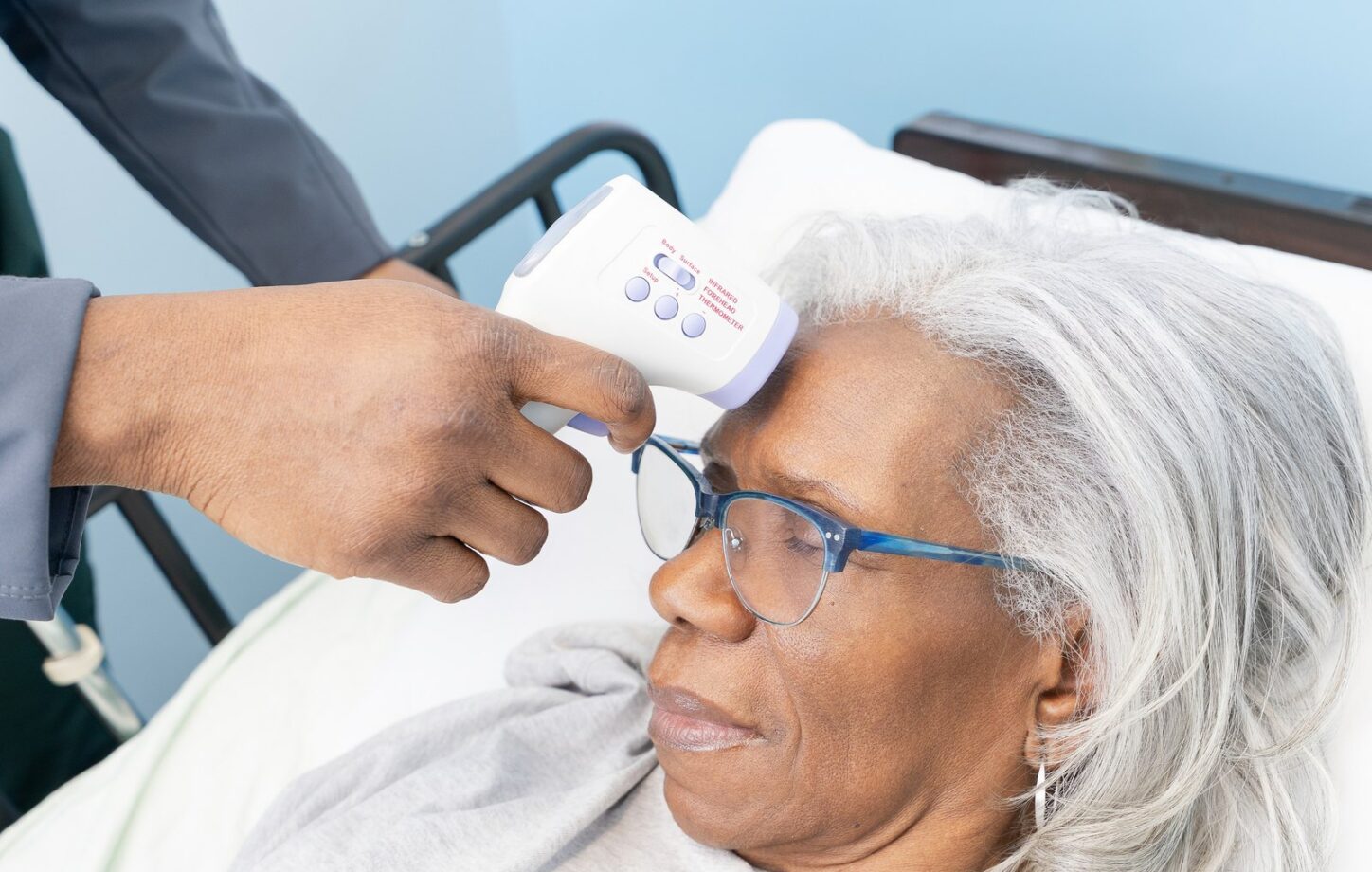 A Care Partner checking a client’s temperature during a home visit