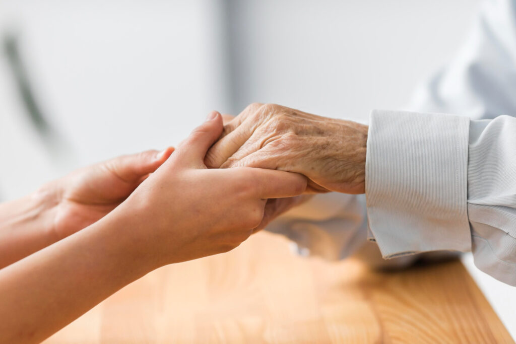 A Care Partner holding an older adult’s hand
