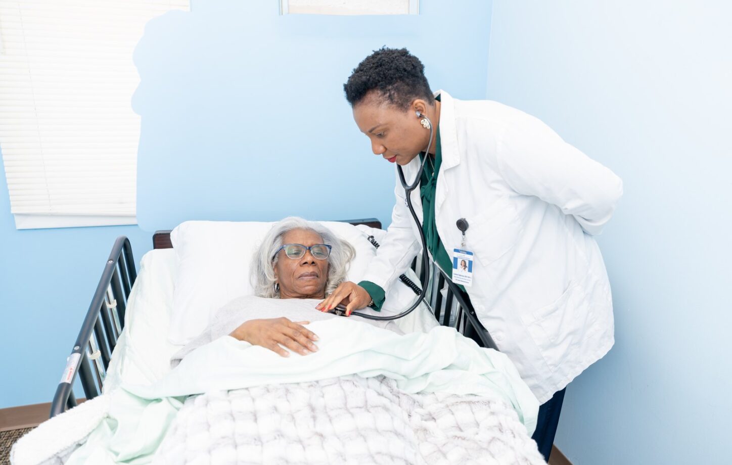A Care Partner sitting with a client at the bedside during a conversation about care